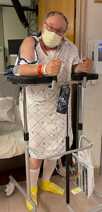 A male patient in a hospital gown standing in a hospital room